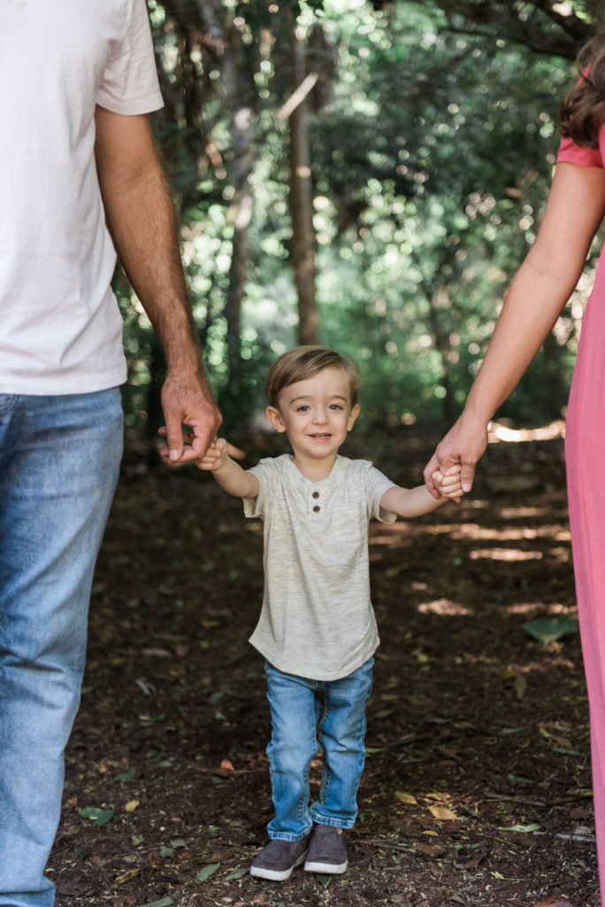 Little boy swinging between mom and dad holding hands