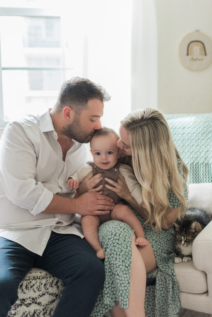 Mom and dad kissing baby