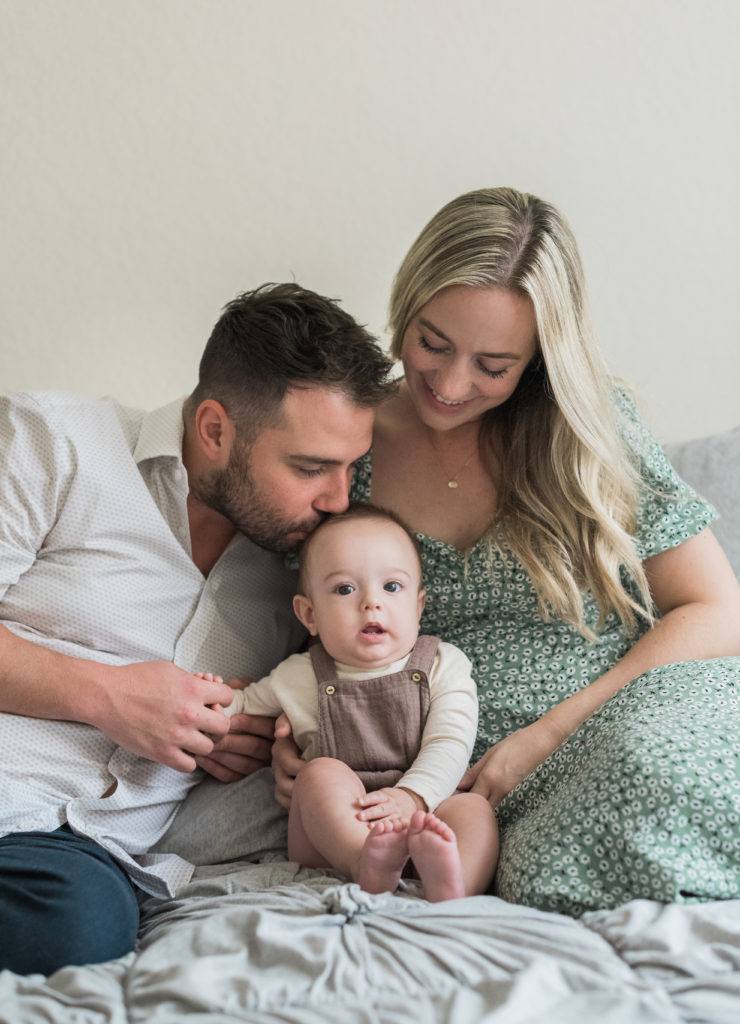 Sitting on bed, dad kissing baby