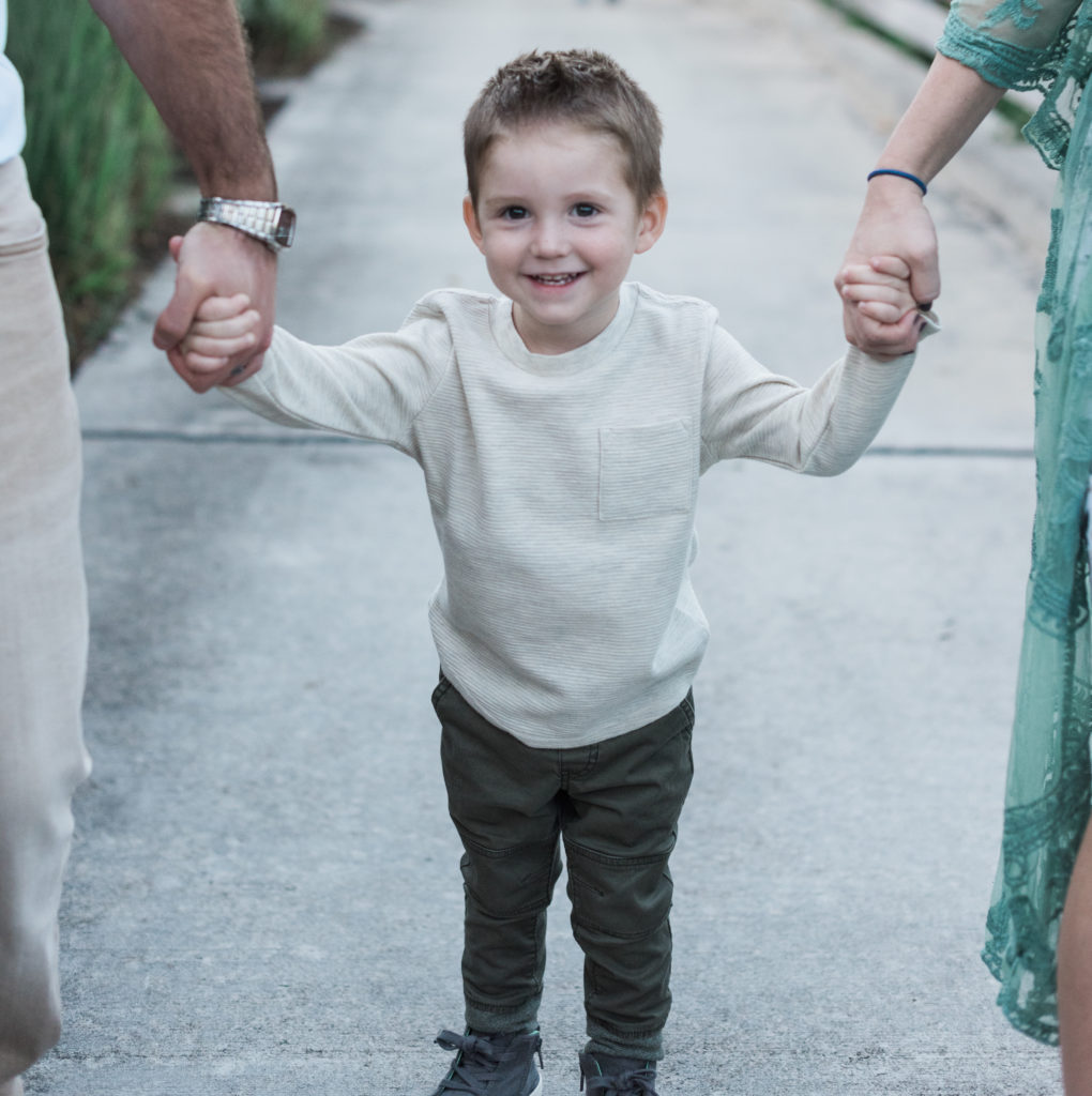 Little boy holding hands with his mom and dad