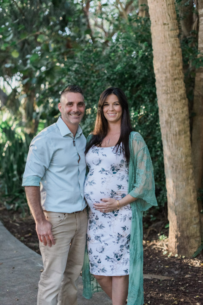 Mom and dad smiling at camera, mom holding belly