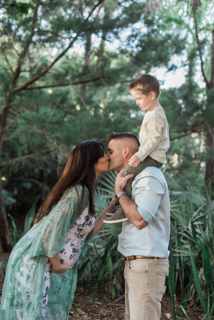 Little boy on dad's shoulders, mom and dad kissing