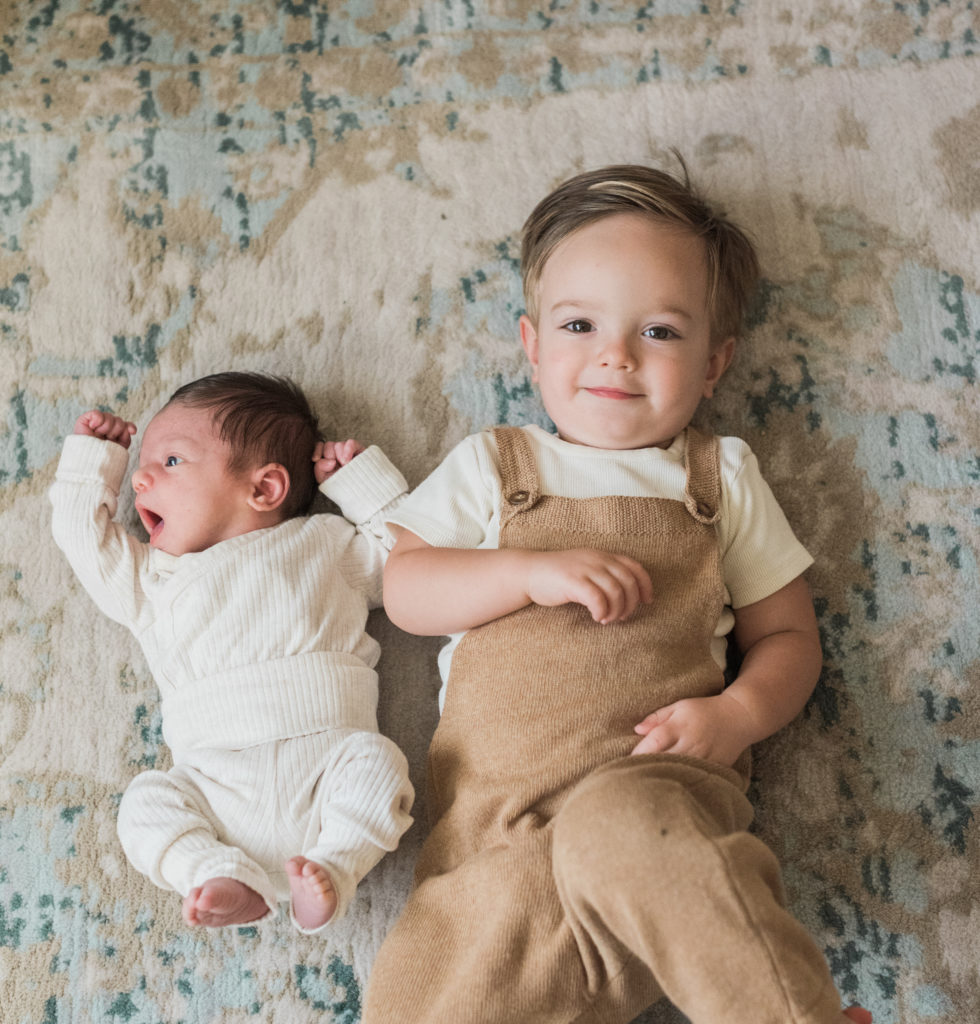 Baby and big brother laying on floor