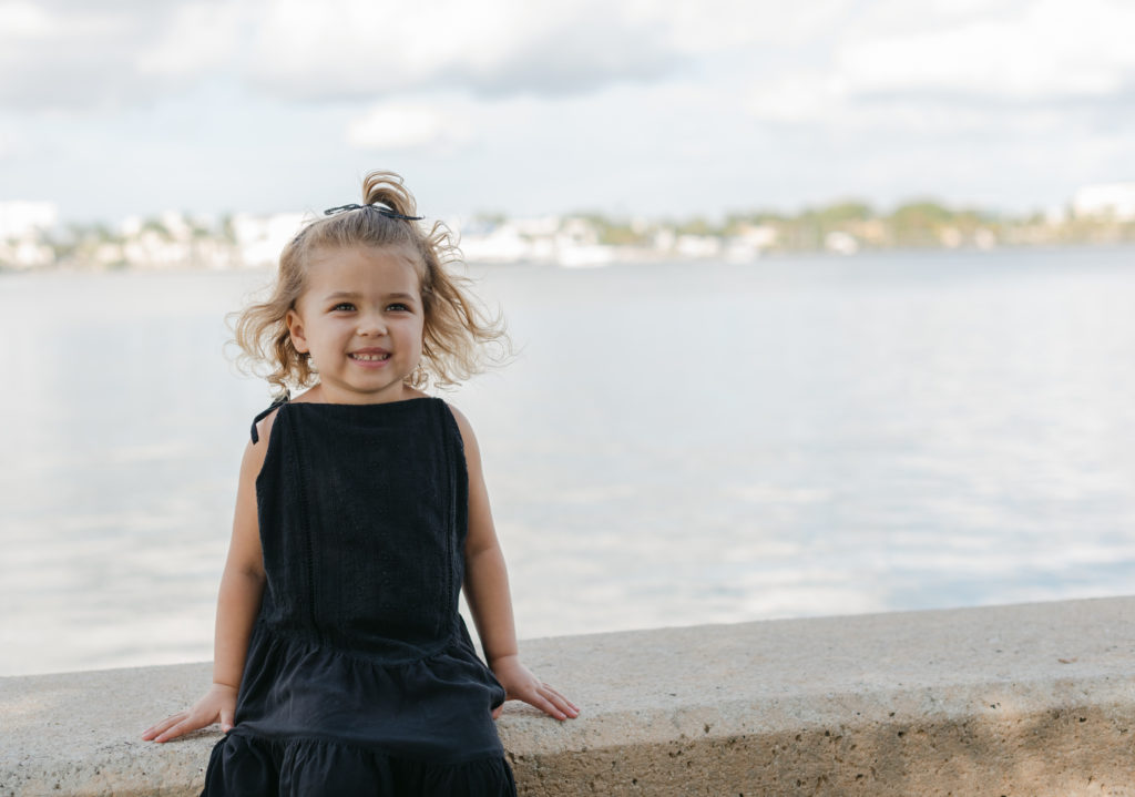 Pull back of girl sitting on ledge smiling