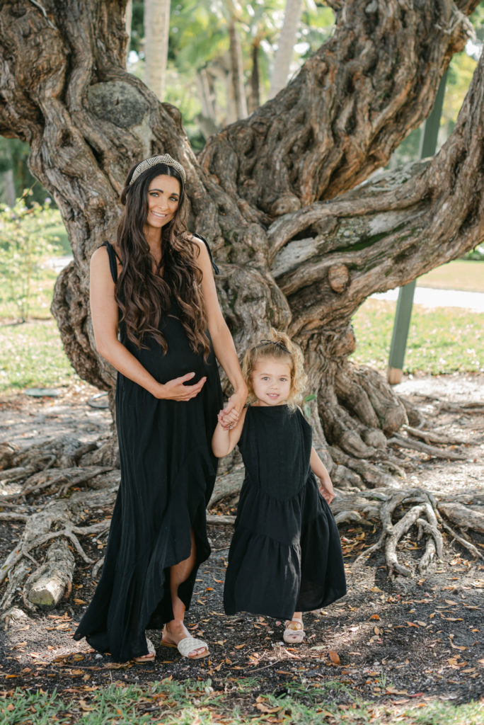 Mom holding belly and hand of daughter