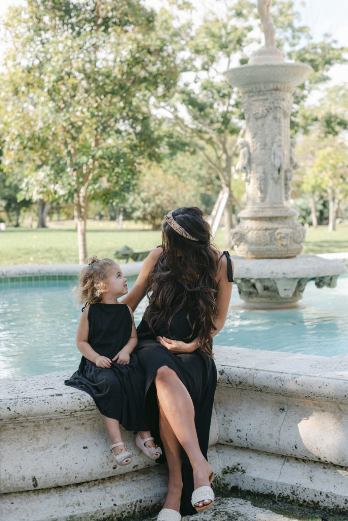 Mom and daughter sitting by fountain looking at each other