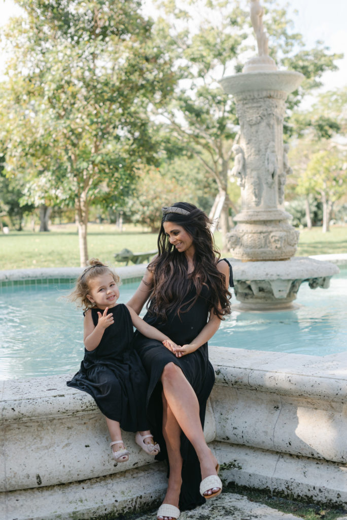 Mom looking at daughter sitting by fountain