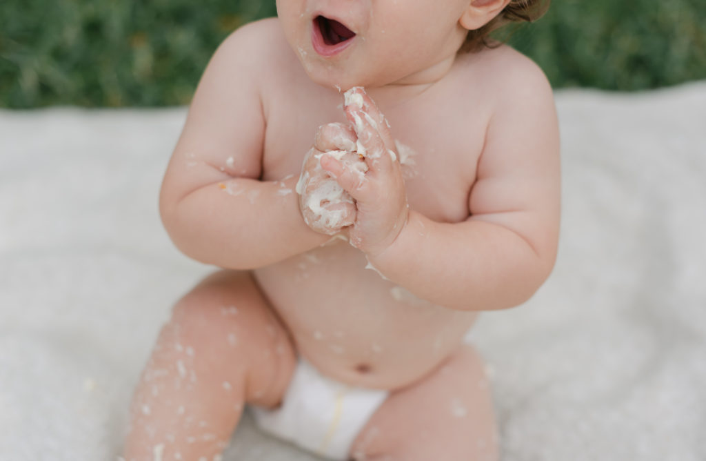 Mouth open, hands clasped covered in cake