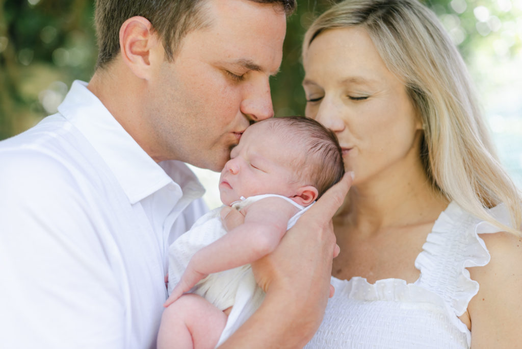 Mom and dad kissing baby girl