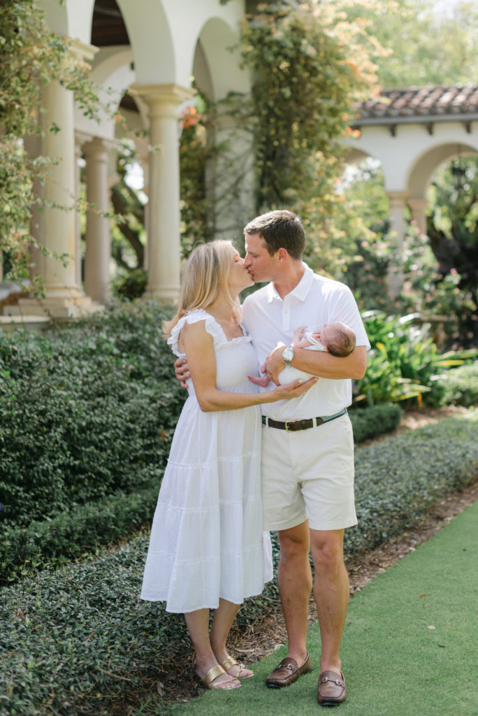 Mom and dad kissing holding baby