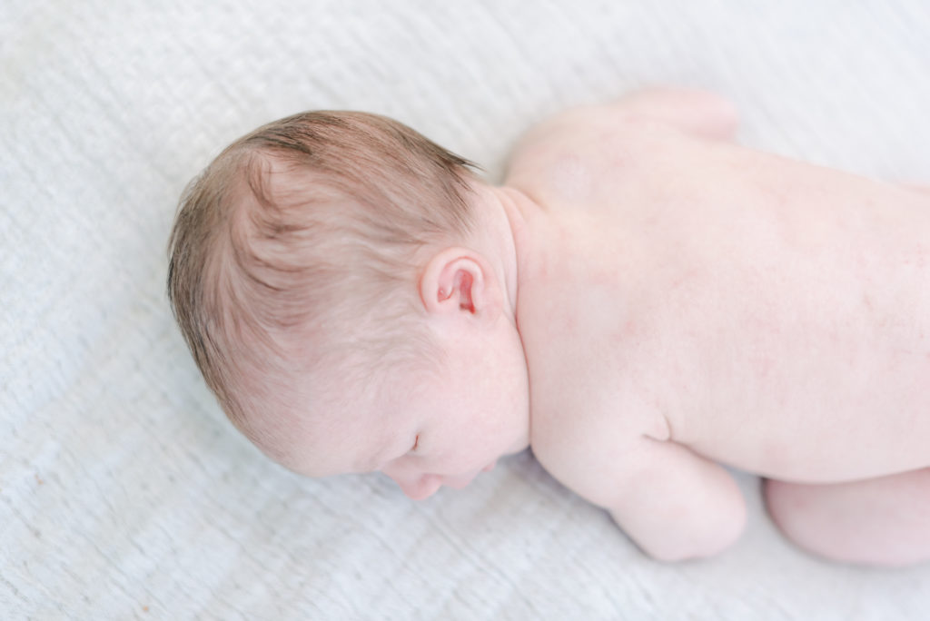 Naked baby girl laying on blanket