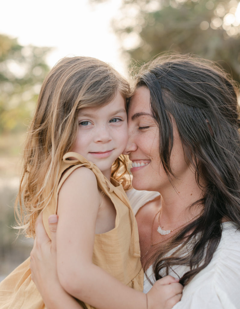 Mom smiling, nuzzled into daughter's cheek