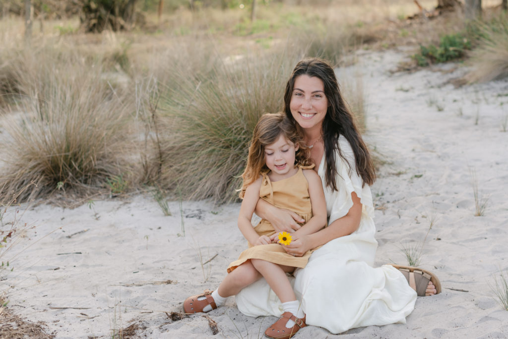 Mom sitting with daughter on her lap holding a flower