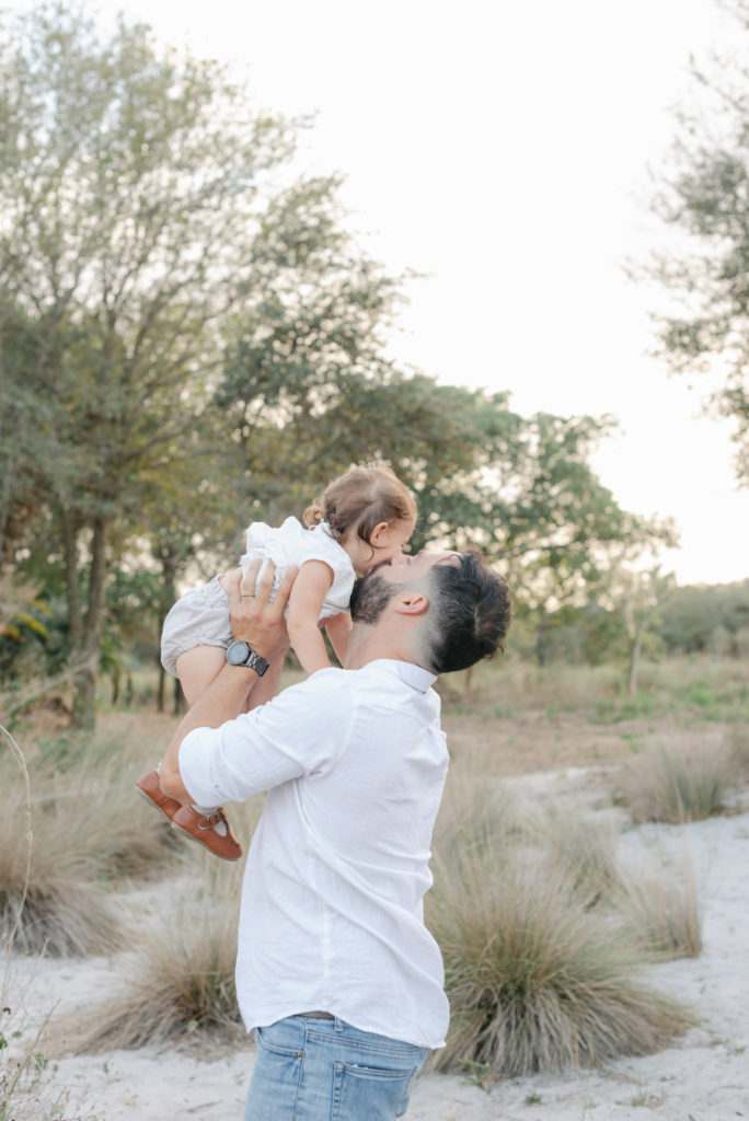 Dad holding up and kissing baby