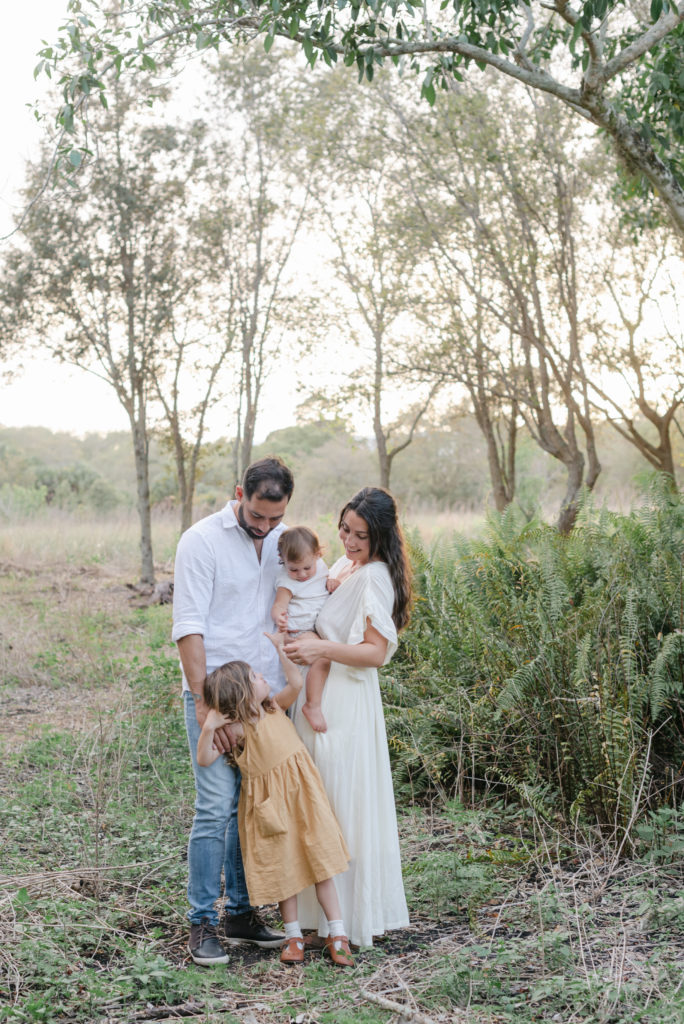 Mom, dad and baby looking down at daughter