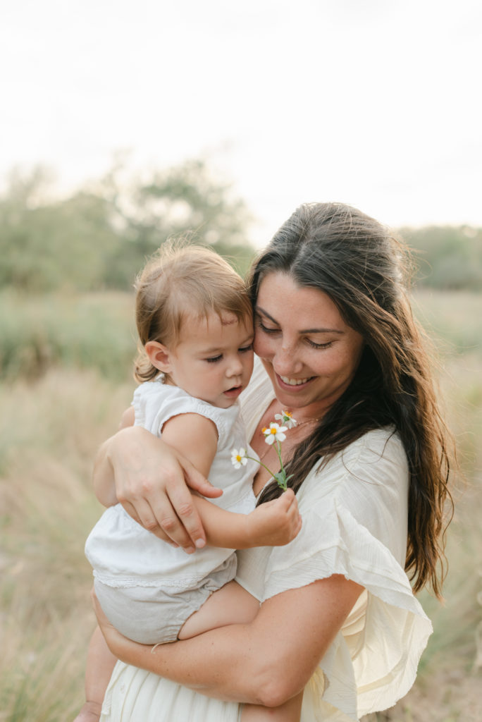 Mom and baby girl looking down at flower