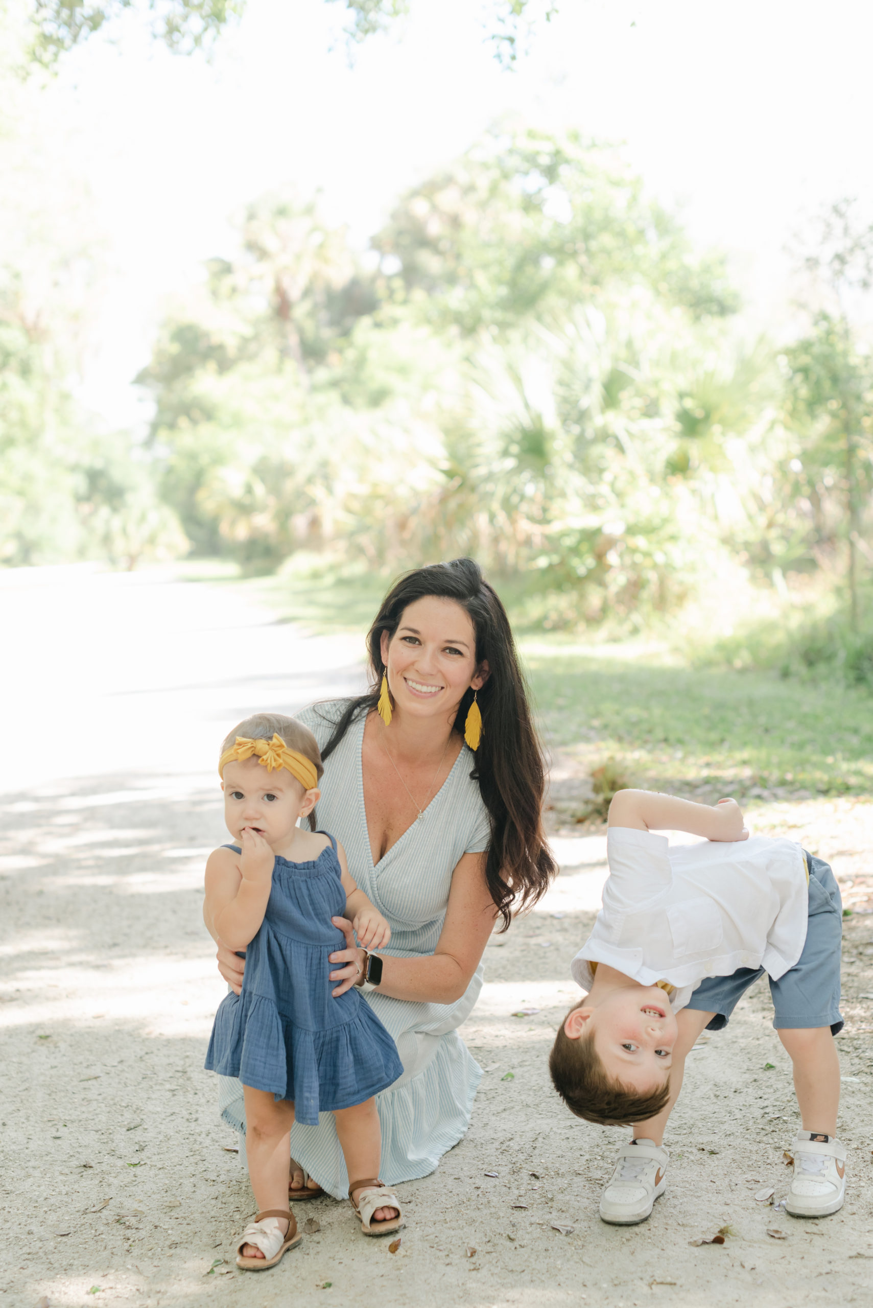 Mom crouched by daughter, son being silly