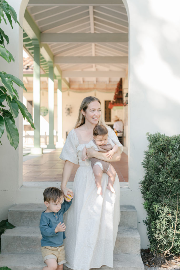 Mom walking down stairs holding baby and holding son's hand