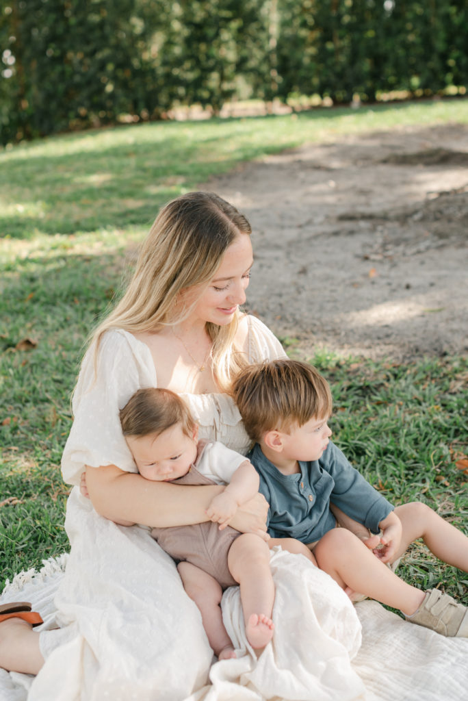 Mom sitting with both sons on her lap, looking down