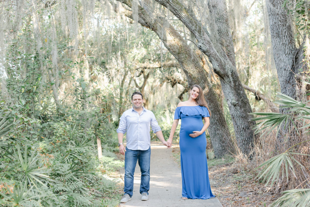 Mom and dad holding hands smiling at the camera