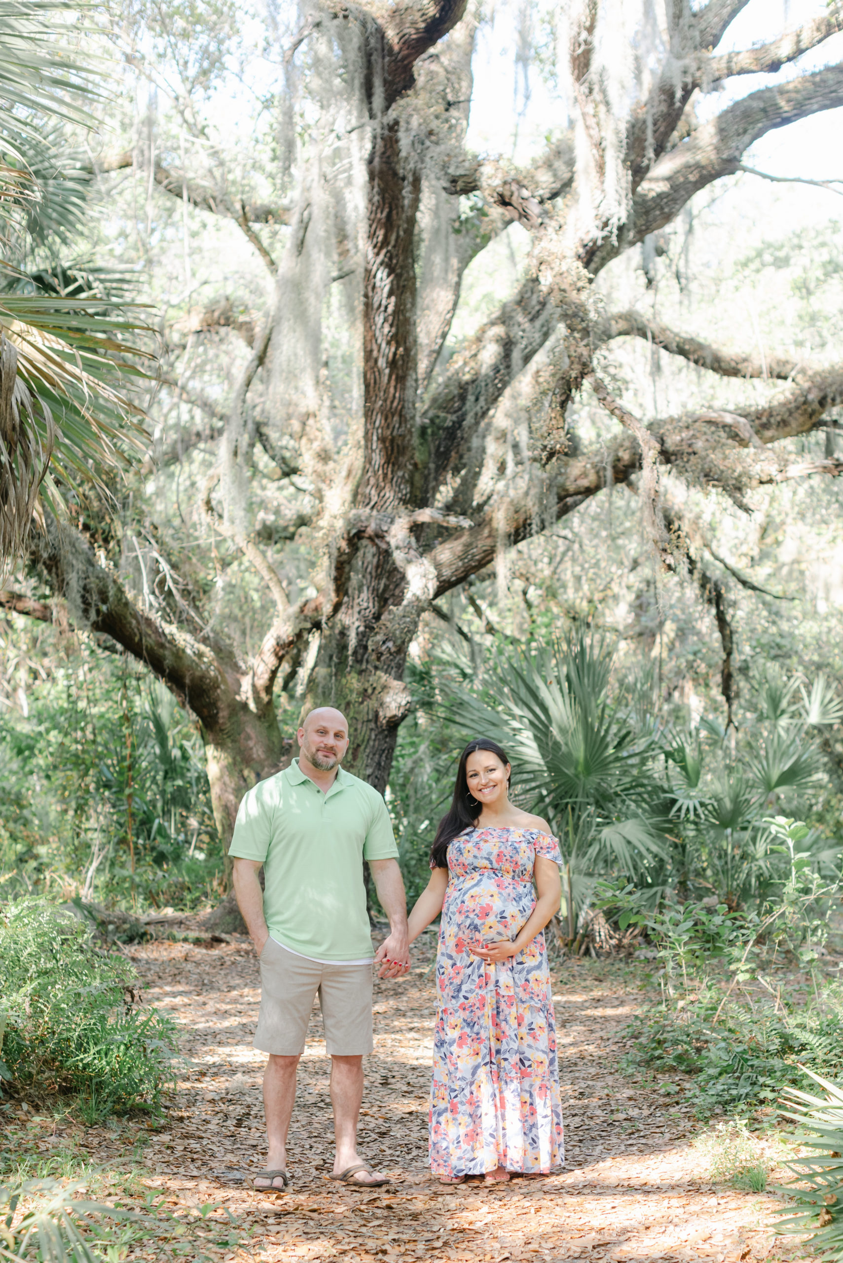 Holding hands smiling under a tree