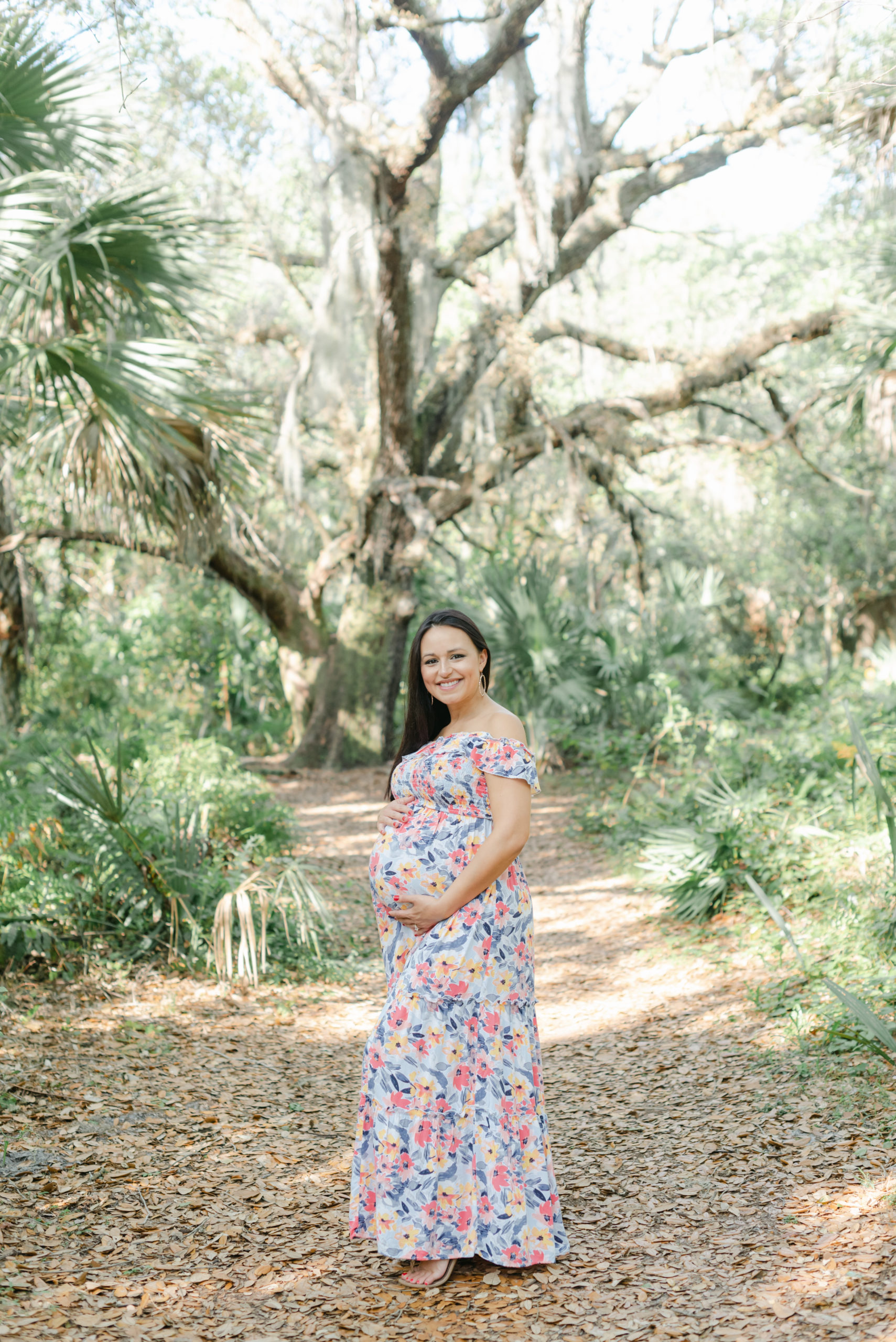 Mom holding belly under Spanish moss tree