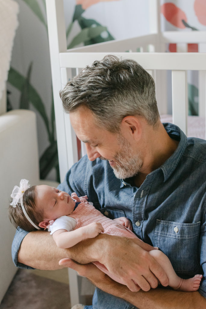 Dad sitting in front of crib smiling at daughter