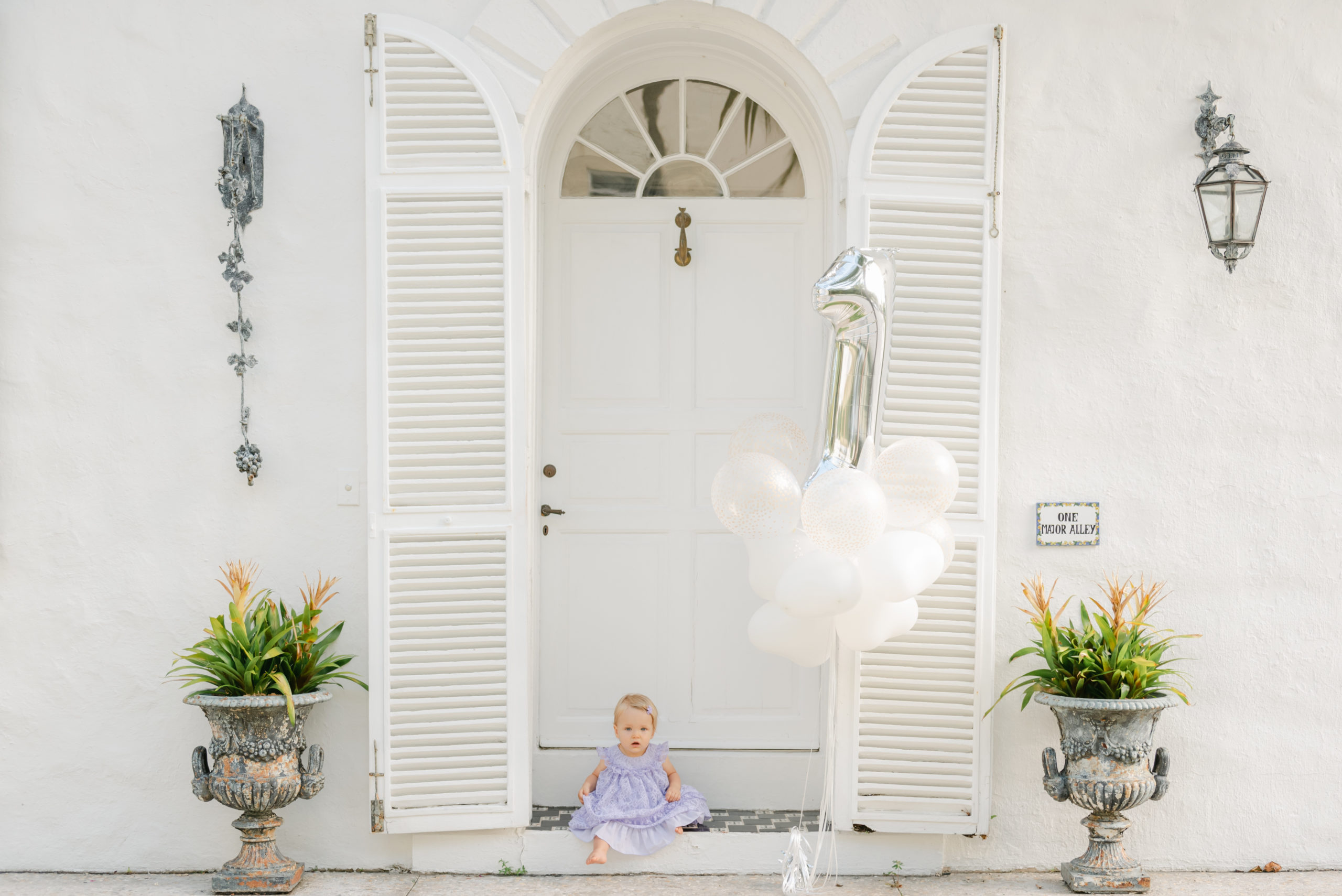 Birthday girl sitting on step in doorway with balloons