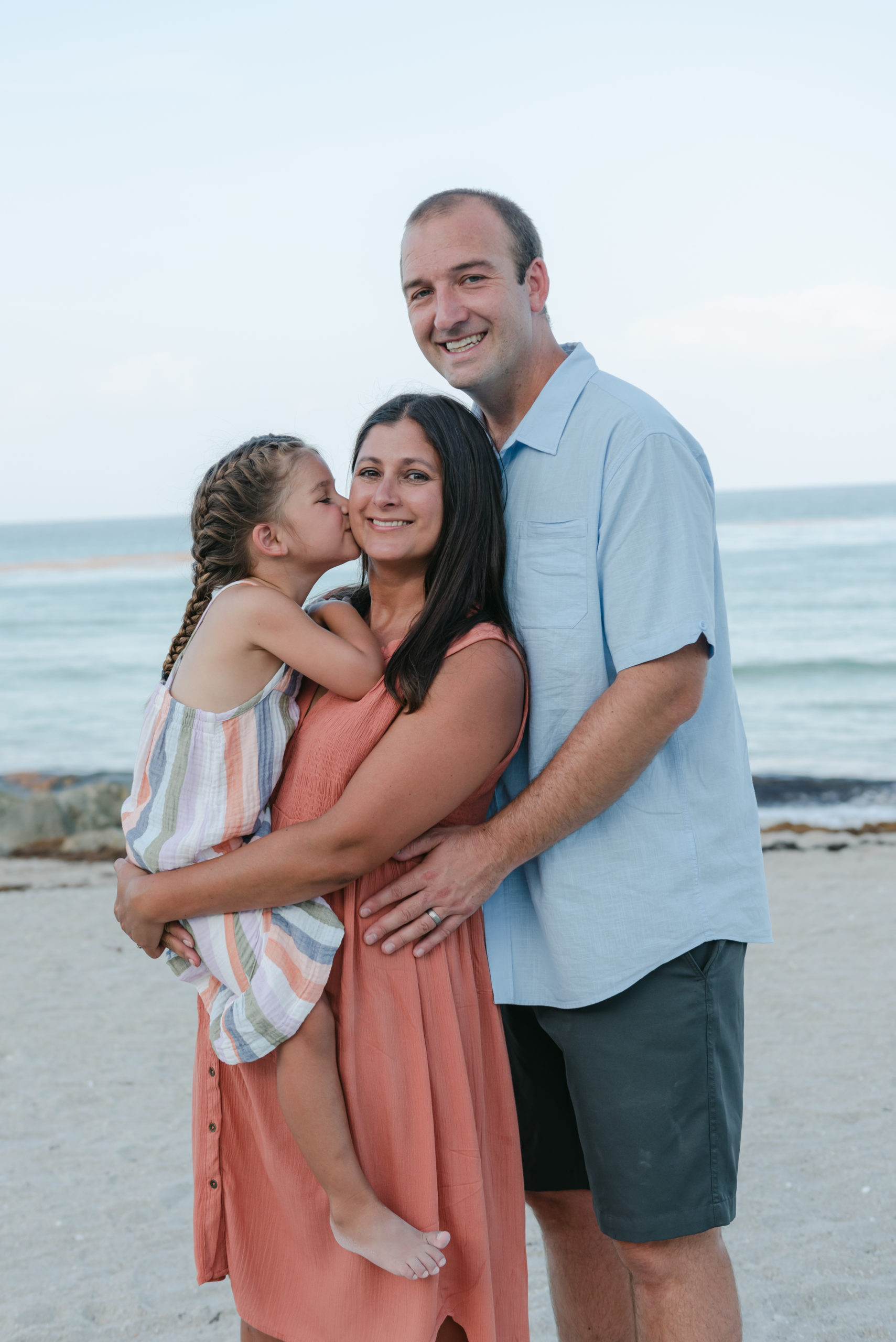 Daughter kissing mom the cheek, dad behind them