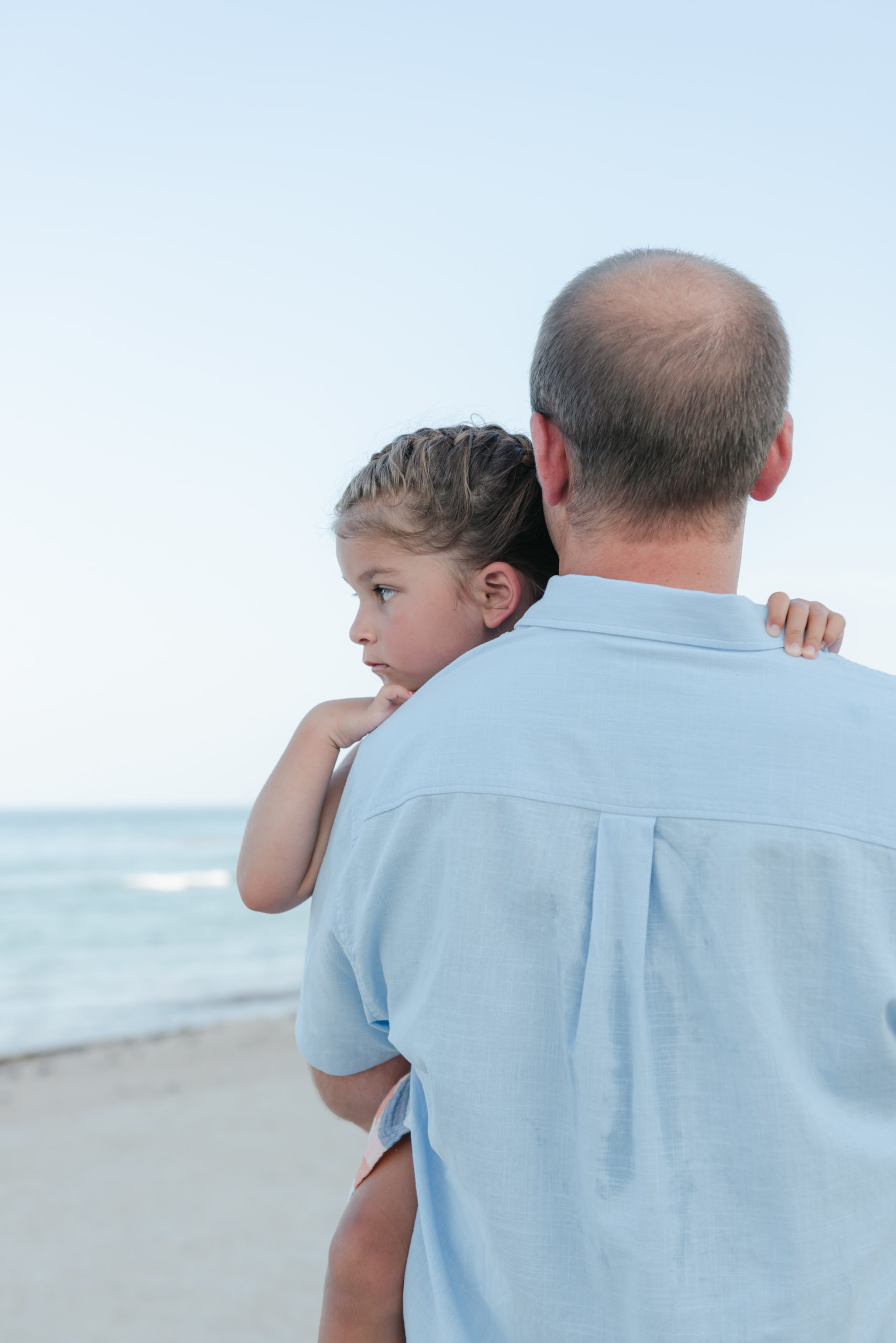 Dad holding daughter looking out to the water