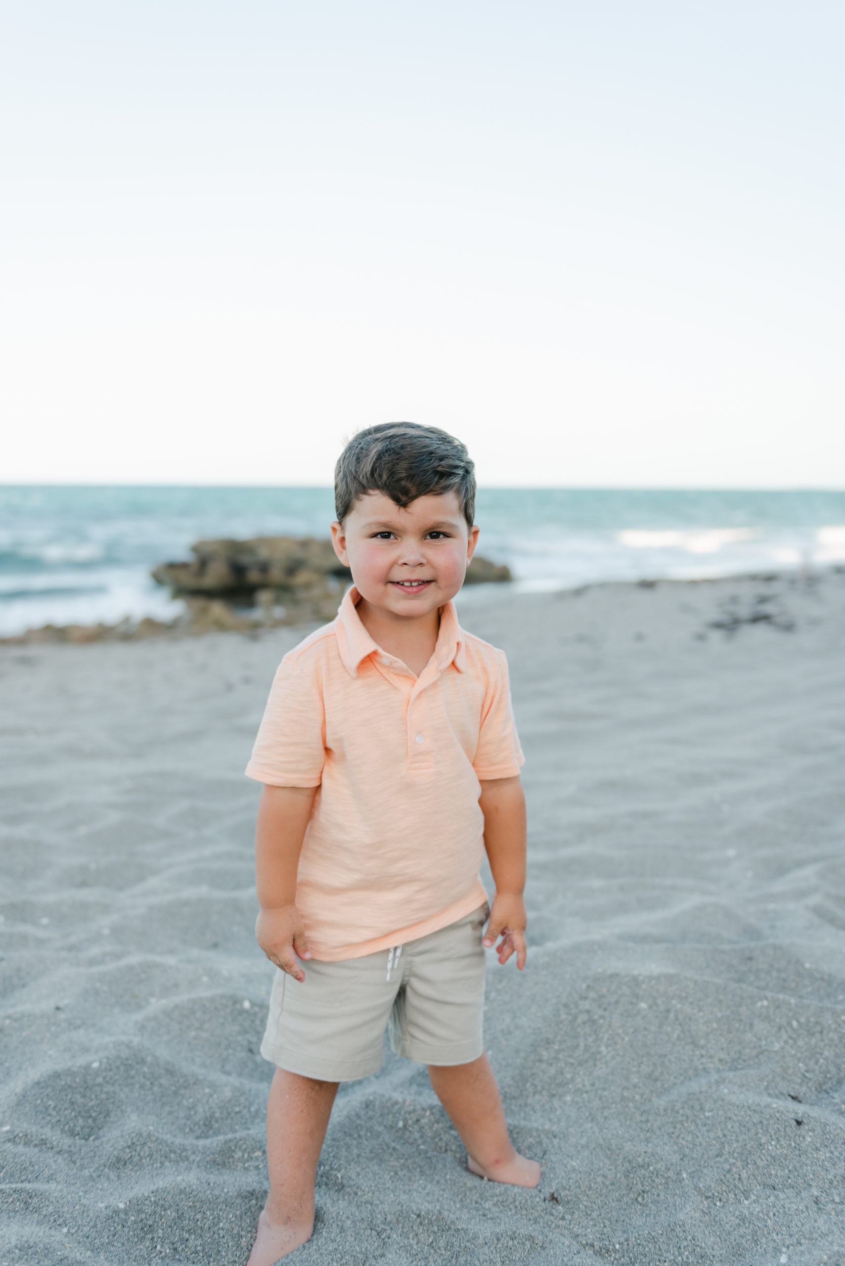 Older son standing in sand smiling