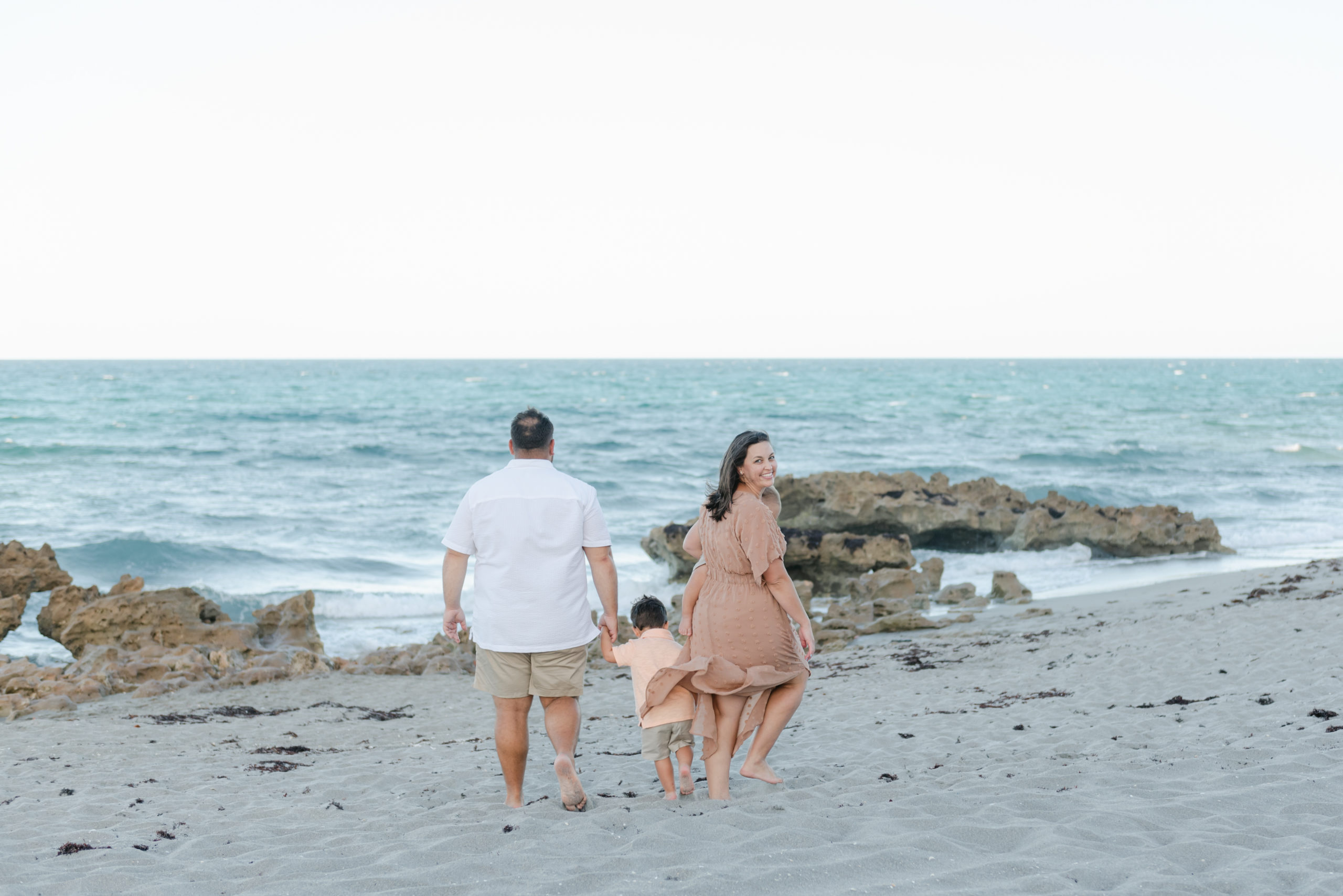 Family walking towards water, mom looking back