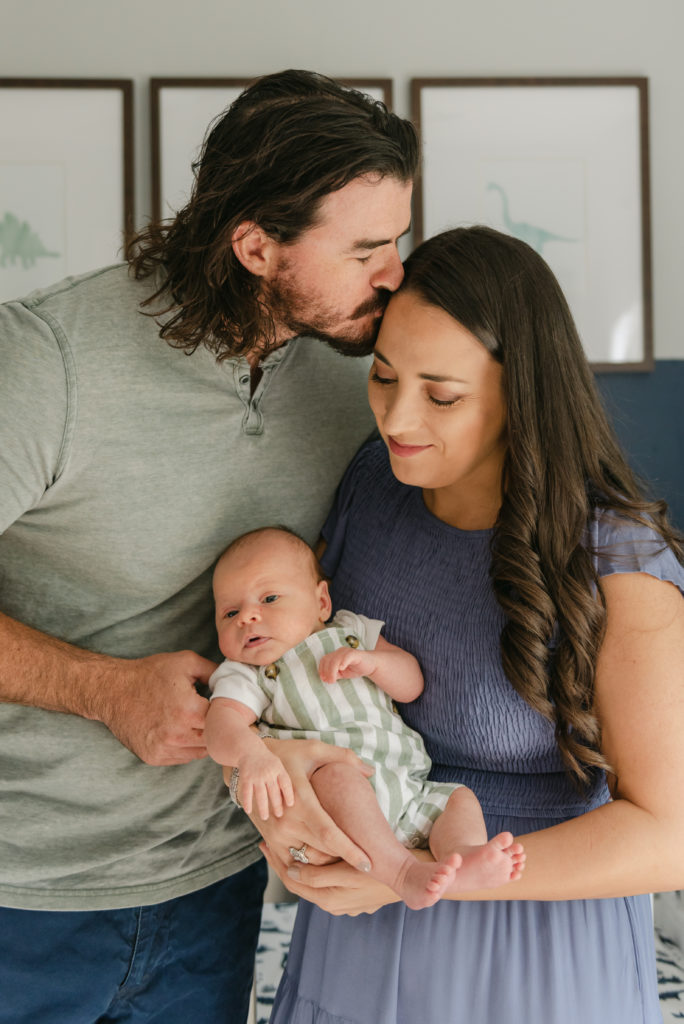 Dad kissing mom's head, mom holding baby 