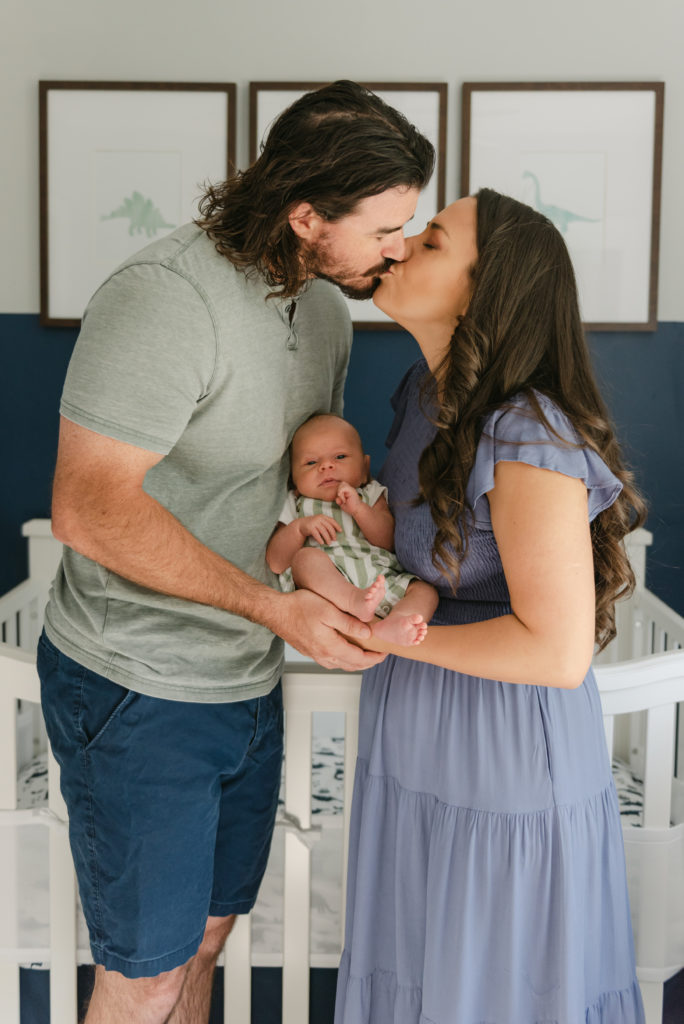 Mom and dad kissing, holding baby between