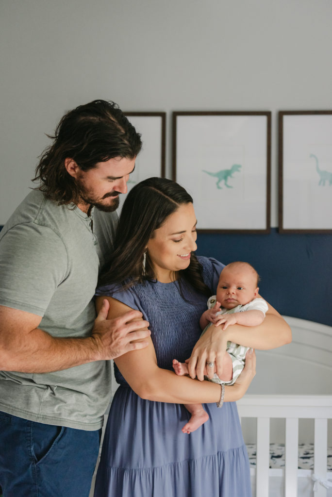 Mom and dad holding baby in front of crib