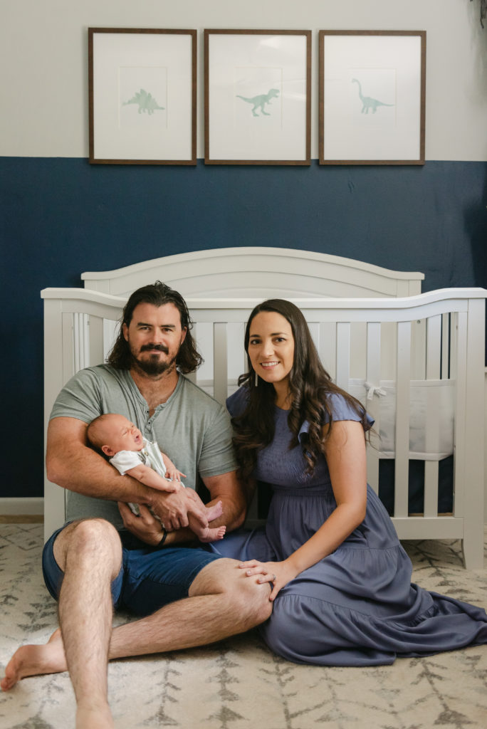 Mom, dad and baby in front of crib