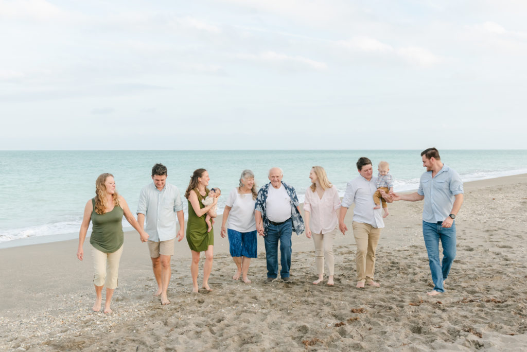 Family walking away from the ocean looking at each other on the beach by Palm Beach family photographer
