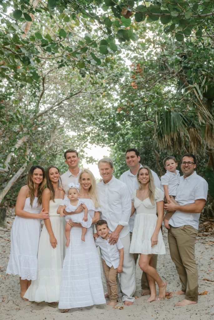Large family dressed in white smiling at the camera by Palm Beach family photographer