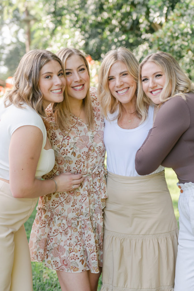 Three sisters and mom huddling up and smiling by Palm Beach family photographer