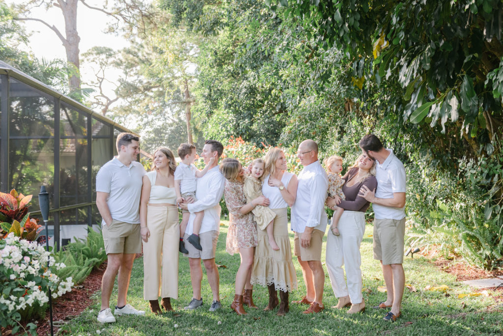 Extended family all looking at each other, smiling by Palm Beach family photographer