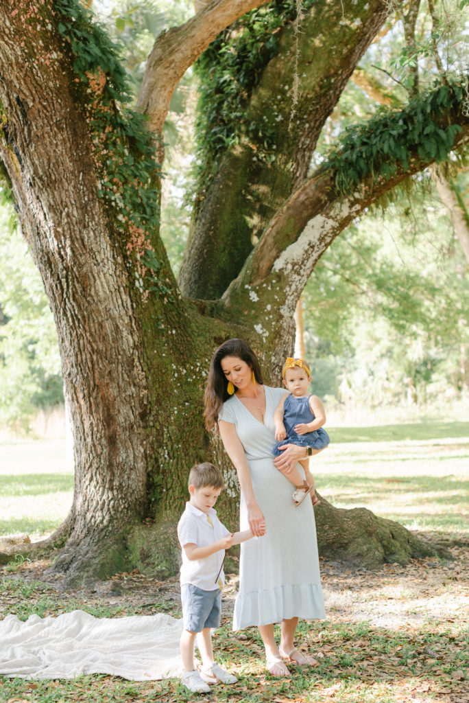 Mom holding sons hand looking at him while holding daughter on hip by Jupiter photographer