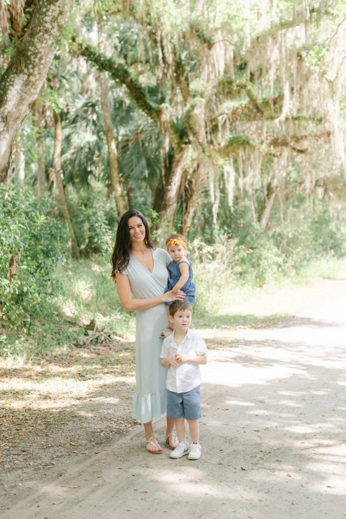 Mom holding daughter and son standing in front under big tree by Jupiter photographer