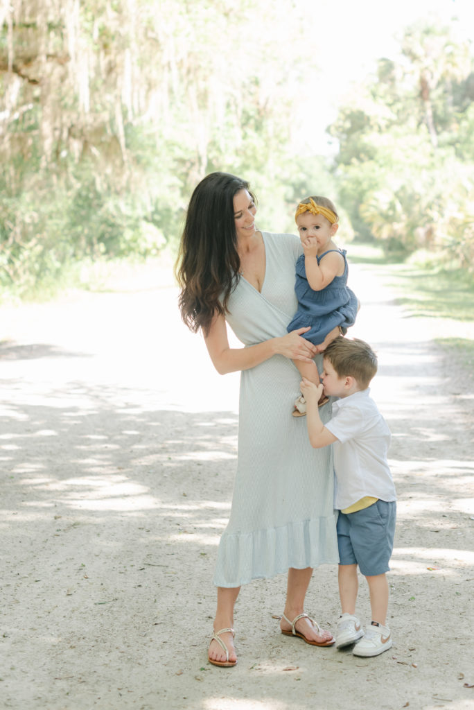 Mom holding daughter, son kissing sisters foot by Jupiter photographer