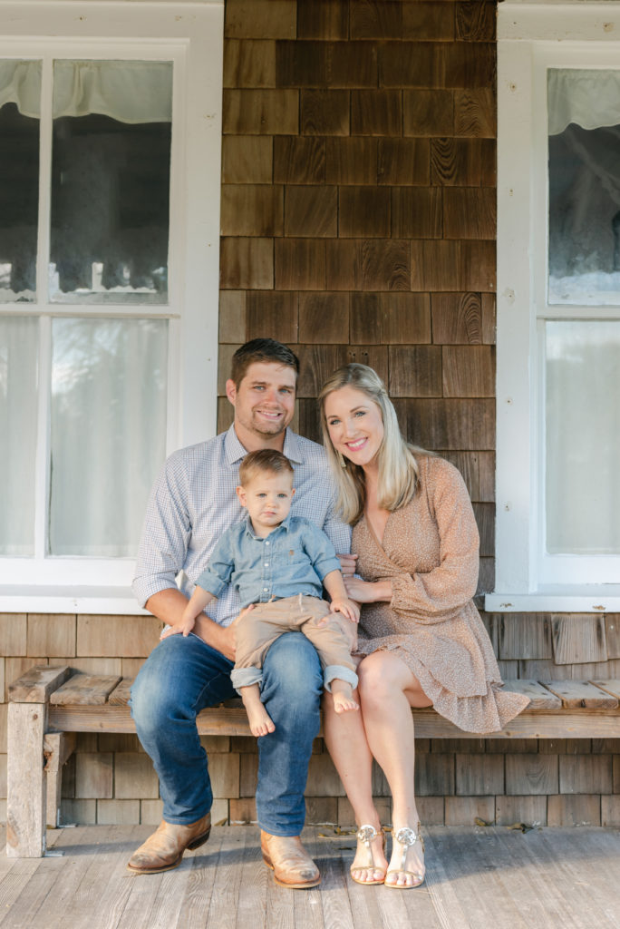 Family of three sitting on bench in front of house by Jupiter photographer