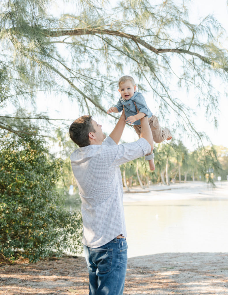 Dad lifting up son under trees by Jupiter photographer