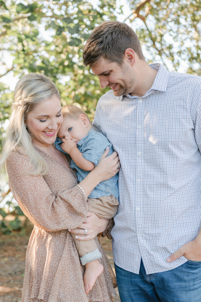 Son snuggled into mom sucking thumb, dad looking at son by Jupiter photographer