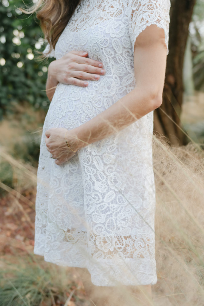 Side profile holding belly in a white dress by Jupiter photographer
