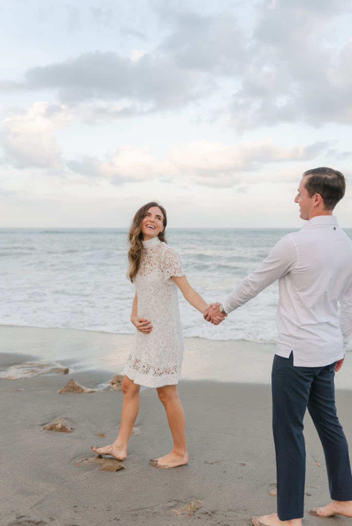 Woman laughing at man holding his hand on beach by Jupiter photographer