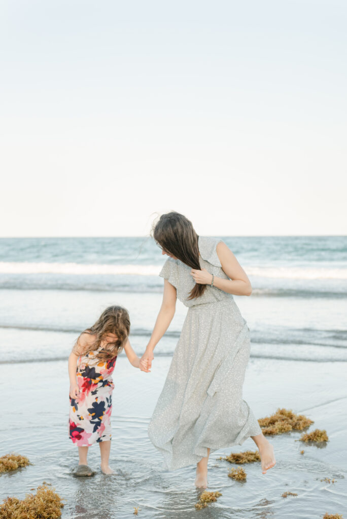 Mom and daughter holding hands walking in the ocean