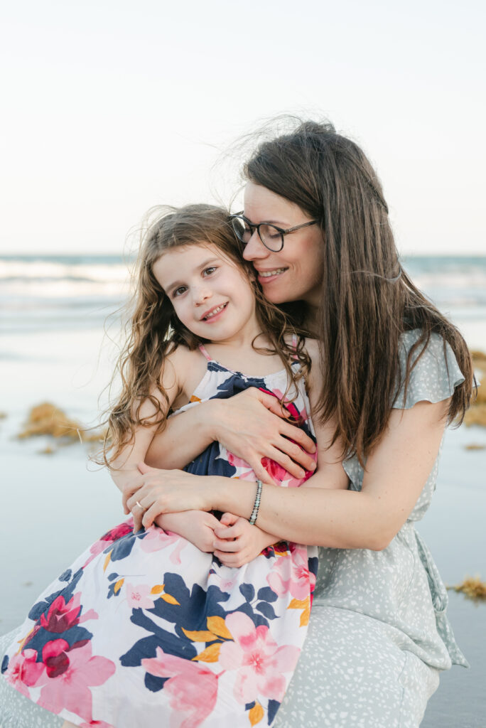 Daughter sitting on mom's lap.  Mom's eyes closed